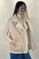 Chaleco tipo gamulán color marrón con interior y bordes de corderito sintético color crema. Presenta cierre frontal y bolsillos laterales con cremalleras metálicas, además de detalles de tiras de cuero sintético.