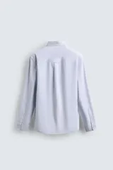 Camisa de corte regular fit confeccionada en tejido de algodón con diseño de rayas verticales. Presenta cuello abotonado, manga larga con puños abotonados, bolsillo plastrón en el pecho y cierre frontal con botones.