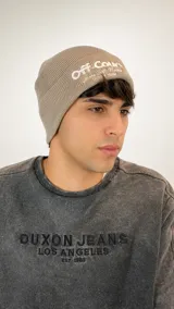 Gorro de lana tipo beanie color beige, con tejido acanalado y bordado frontal con la inscripción Off Court.