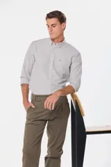 Pantalón de vestir color verde oliva, de corte recto, con bolsillos laterales y traseros. Se ajusta a la cintura con cinturón de cuero marrón.