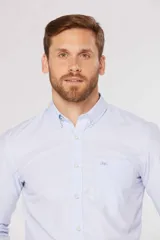 Camisa de manga larga con diseño de rayas finas en color celeste, cuello con botones y bolsillo ojal en el pecho.