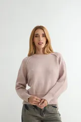 Buzo de tejido de punto en color rosado, con cuello redondo, mangas largas y puños acanalados. Presenta un diseño de tejido texturizado en la parte inferior y en los puños.