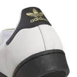 Zapatillas Adidas Superstar ADV color blanco hueso con puntera de goma negra, tres tiras laterales negras y contrafuerte trasero negro.