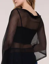 Poncho liviano de tejido de punto fino calado, color blanco, con silueta asimétrica envolvente, escote bote drapeado y mangas integradas estilo capa.