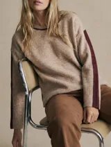 Sweater de tejido de punto con calce oversize, color beige con detalles en color bordó en el cuello y franjas laterales en las mangas. Presenta puños y ruedo acanalados.