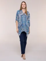 Blusa holgada de poliéster con estampado de arabescos en tonos azules, escote en V con botones frontales, mangas 3/4 y ruedo asimétrico en punta.