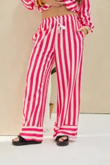 Pantalón largo de corte ancho, con estampado de rayas verticales en colores fucsia y blanco. Cuenta con cintura elástica ajustable con cordón y bolsillos laterales.