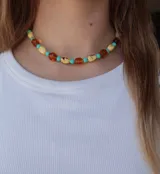 Gargantilla de cuentas con diseño colorido que alterna esferas turquesas, cuentas alargadas amarillas con detalles oscuros y cuentas facetadas de color ámbar.