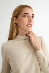 Polera de punto color beige, con cuello alto y mangas largas, de diseño básico y ajuste clásico.