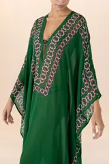 Kaftán largo verde oscuro con patrón geométrico en rosa y blanco, semi-traslúcido, con mangas amplias y escote en V con aplique central.