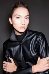 Chaqueta de eco cuero negro con costuras a la vista en tono contrastante, cuello mao con solapas estructuradas y cierre frontal de botones.