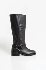 Botas de caña alta confeccionadas en cuero negro, con diseño de estilo western que incluye una correa decorativa con argollas metálicas y remaches en el tobillo. Presentan una puntera cuadrada y un taco bajo cuadrado.