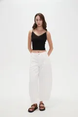 Musculosa crop de morley negro con tirantes finos, escote en V decorado con detalles de encaje y un pequeño lazo en el centro.