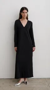 Vestido largo de corte recto y diseño minimalista, con escote en V profundo y mangas largas. Presenta tajos laterales en el ruedo.