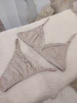 Conjunto de lencería compuesto por un bralette triangular y una bombacha tipo colaless, confeccionados en algodón color nude con delicados detalles de encaje en los bordes.