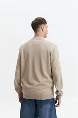 Campera tejida de punto color beige, con cuello rib, puños y bolsillos laterales.