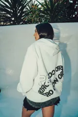 Hoodie blanco de corte oversize con capucha y diseño estampado en la espalda con letras negras.