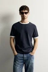 Camiseta regular fit gris melange con cuello redondo y mangas cortas. Presenta acabados con rib en contraste de color marrón oscuro en el cuello y los puños.