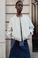 Chaqueta bomber de cuello redondo y manga larga con diseño holgado. Presenta cierre frontal con cremallera, bolsillos delanteros de vivo y acabados elásticos en los puños y el ruedo.