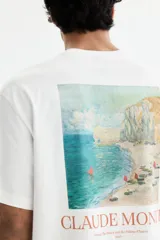 Remera de algodón de corte holgado con cuello redondo y hombros caídos. Presenta un estampado minimalista con el nombre Claude Monet en el pecho.