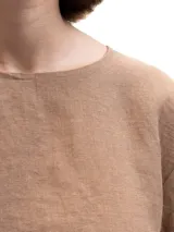 Remera de lino con corte holgado, cuello redondo y mangas cortas. Presenta un diseño minimalista con detalle de botones en la espalda.