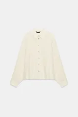Camisa de cuello solapa y manga larga con sisa ancha, confeccionada en tejido con hilo metalizado y cierre frontal con botones.