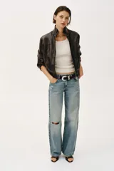 Chaqueta estilo bomber corta de efecto piel en color marrón oscuro, con cuello subido, cierre frontal con cremallera y cintura elástica fruncida.