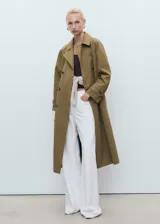 Abrigo tipo trench de diseño recto y oversize, color verde oliva. Presenta cierre de doble botonadura, cuello de solapa ancha, bolsillos laterales y mangas largas con puños abotonados. Incluye forro interior y cinturón desmontable.