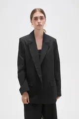 Blazer de corte holgado con cuello solapa, cierre frontal con botón y bolsillos laterales con solapa.
