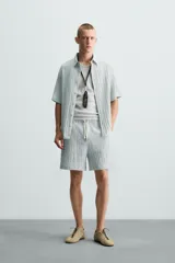 Bermuda negra de corte regular, confeccionada en tejido jacquard con efecto arrugado. Presenta cintura elástica ajustable con cordón blanco, bolsillos laterales y bolsillos traseros de vivo.