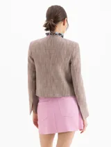 Chaqueta de lino y viscosa con estampado cuadrillé en tonos marrones y beige, de corte regular y largo a la cintura. Cuenta con cuello redondo, cierre frontal con botones dorados grabados, bolsillos frontales con solapa y bolsillos plaqué.
