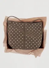 Bolso tipo hobo de cuero gamuzado color marrón, con diseño de tachas metálicas plateadas distribuidas por toda la superficie. Cuenta con una correa de hombro integrada y cierre superior.