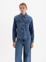 Camisa de denim con lavado clásico, corte entallado en la cintura y silueta evasé hacia el ruedo. Presenta cuello camisero, cierre frontal con botones metálicos y dos bolsillos con solapa en el pecho.