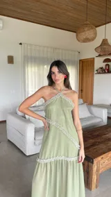 Vestido largo de gasa color verde sage, con escote halter y espalda regulable. Presenta detalles de volados fruncidos en diagonal a lo largo del diseño.