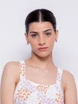 Vestido corto blanco con estampado floral en tonos naranja y lila, de corte suelto y sin mangas.