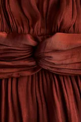 Vestido corto marrón de tejido drapeado con cuello redondo, manga larga abullonada y detalle de nudo en la cintura con tiras colgantes.