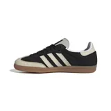 Championes Adidas Samba OG, color negro con detalles en blanco y suela de goma marrón. Inspirados en el modelo icónico de fútbol sala de los años 50, con parte superior de cuero suave, punta reforzada y las emblemáticas 3 Tiras.
