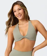 Top deportivo Fabletics modelo PureLuxe color verde militar, con diseño cruzado en la parte delantera y tirantes halter.
