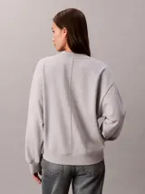 Buzo Calvin Klein de tejido terry color gris melange, con cuello en V, manga larga y costura vertical central en el frente.