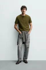 Camiseta de manga corta con cuello panadero y cierre frontal de tres botones. Presenta una textura acanalada y un corte regular fit.