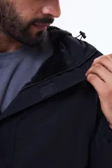 Buzo tipo canguro de nylon color negro, con capucha ajustable, cierre frontal parcial y bolsillo tipo sobre en el pecho.