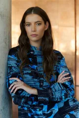 Vestido camisero largo con estampado geométrico en tonos camel y negro. Cuenta con mangas largas con puños, un bolsillo frontal amplio, botones frontales y un botón de cierre en el cuello.