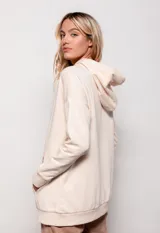 Canguro oversize color beige, de tela deportiva, con capucha ajustable con cordones y bolsillo tipo canguro en el frente.