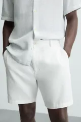 Bermuda azul marino de corte regular fit, confeccionada en tejido de algodón y lino. Cuenta con bolsillos frontales y traseros, cierre frontal con cremallera y botón.