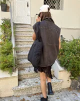 Chaleco de denim color gris oscuro con efecto lavado, corte oversize, cuello camisero, cierre frontal con botones metálicos y dos bolsillos frontales con solapa.