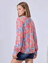 Blusa estampada con cuello a la base, escote en V y aplique de puntilla. Terminación de ruedo con nudo.