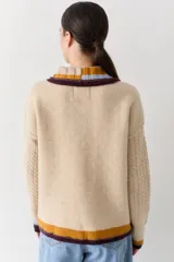 Buzo de lana tipo polo con cuello y cartera de botones en colores contrastantes. Presenta mangas con textura de ochos y puños y ruedo con terminaciones en franjas de colores.