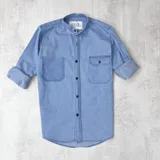 Camisa celeste de jean con cuello mao, manga larga con puños abotonados y bolsillo en el pecho.