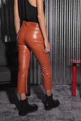Pantalón de tela engomada color camel, de corte capri semi oxford y tiro medio-alto. Presenta bolsillos traseros y cierre con botón metálico.