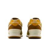 Championes New Balance 574 de mujer, en tonos mostaza y marrón, con entresuela ENCAP y el logotipo "N" en los laterales.